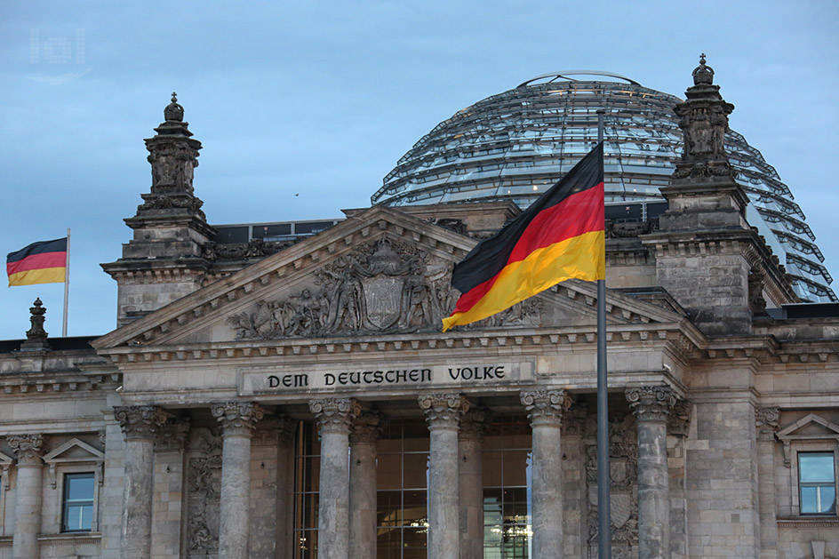 Berliner Reichstagsgebäude mit Glaskuppel und Deutschland-Fahnen