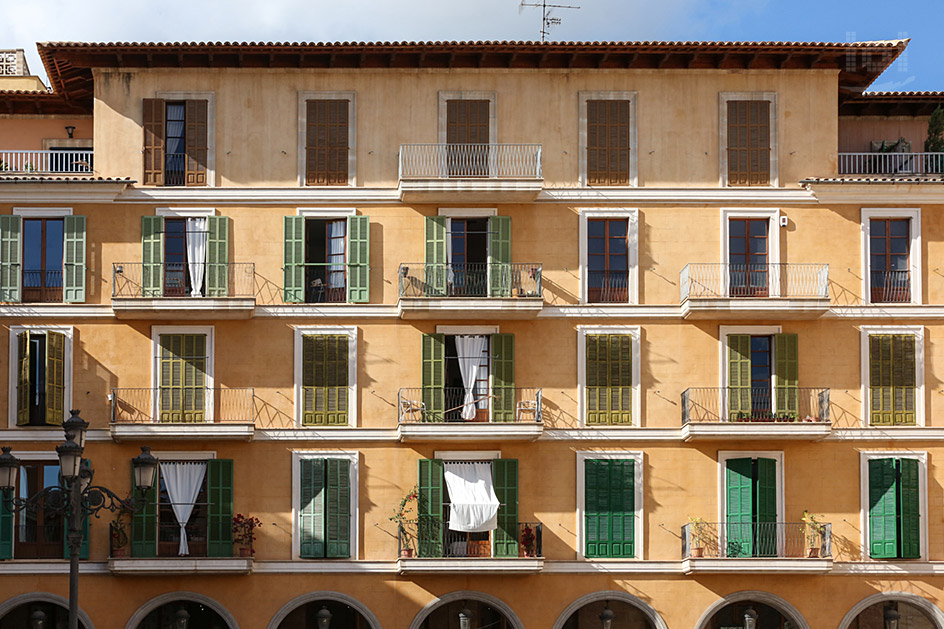 Mediterrane Häuserfassade mit vielen Fenstern, Fensterläden und Vorhängen