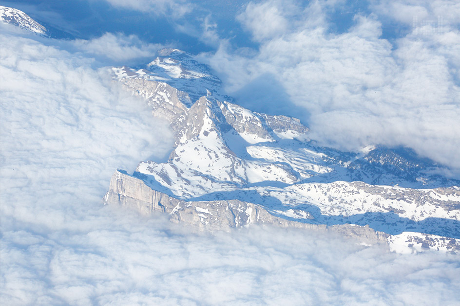 Aussicht vom Flugzeug aus auf schneebedeckte Berge in den Wolken