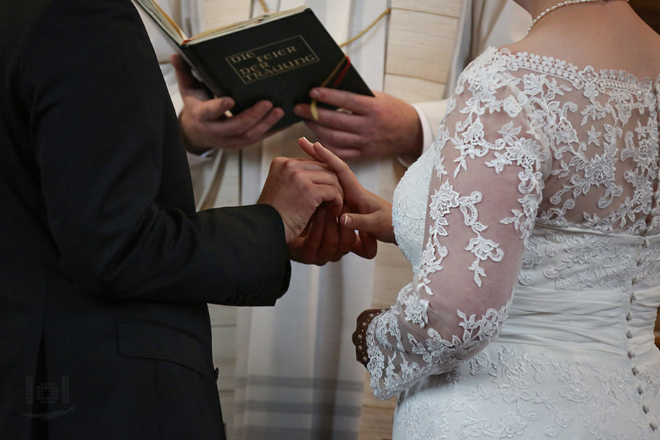 Bräutigam steckt seiner Braut den Ring an bei einer kirchliche Trauung