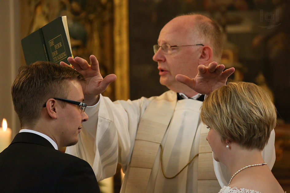 Hochzeitspaar und Priester bei der kirchlichen Trauung
