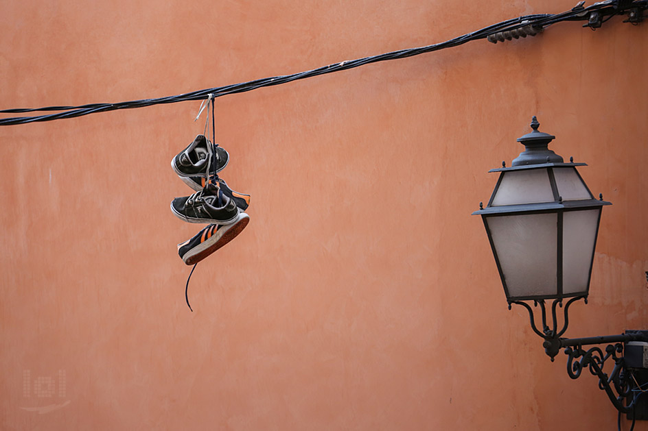 Zwei Paar Turnschuhe hängen an einem Kabel vor einer Hauswand