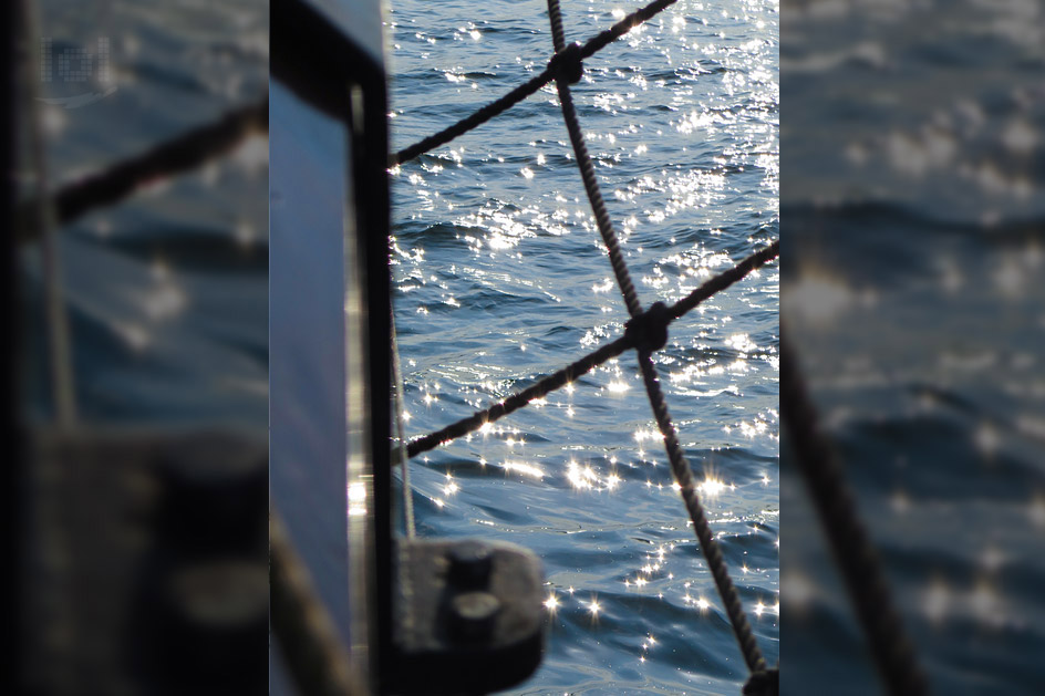 Glitzerndes Wasser und Blick durch ein Netz des Segelbootes