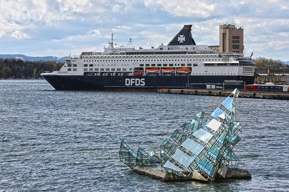 Kreuzfahrtschiff im Hafen von Oslo mit glaeserner Skulptur im Wasser