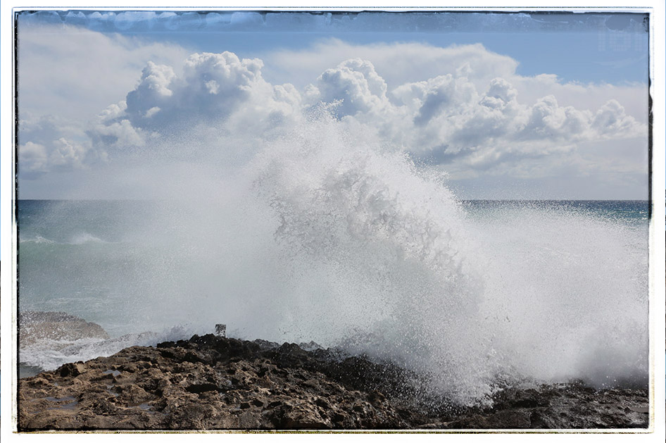 Große Welle bricht mit Wucht an einem Felsen
