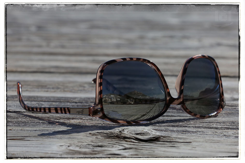 Sonnenbrille mit Spiegelung auf einem Holzsteg